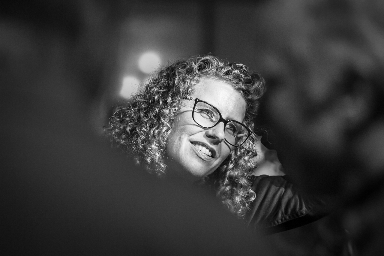 A corporate event attendee is photographed with two people in the foreground to create an interesting viewpoint. This image was taken with available light in a dark outdoor venue.