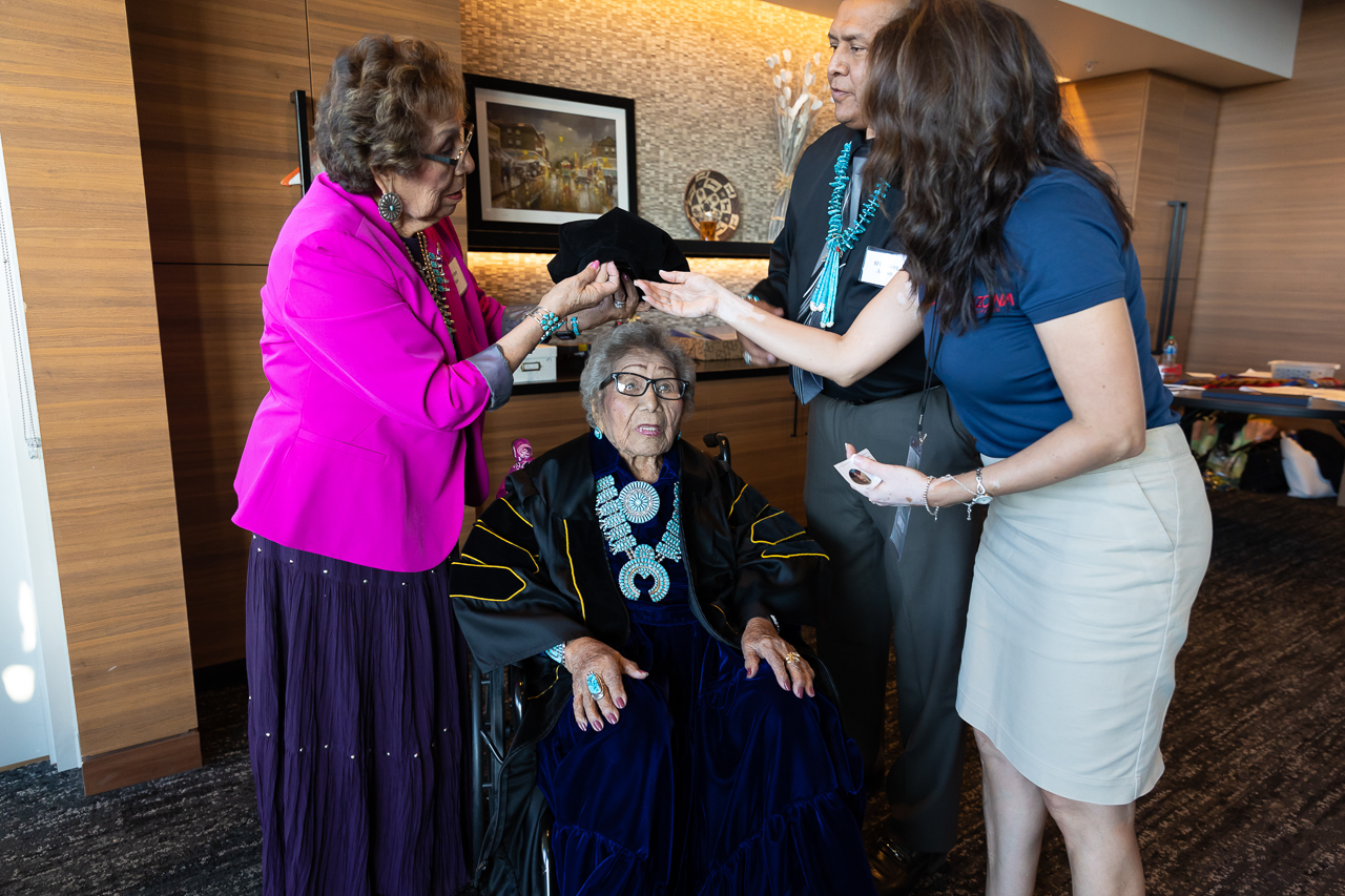 Honoree Louva Dahozy is a Diné knowledge holder, health educator, cultural teacher and voters' rights activist born in the 1920s on the Navajo Nation. In this image, Ms.Dahozy is assisted by her family in preparation of the 2022 University of Arizona Commencement.