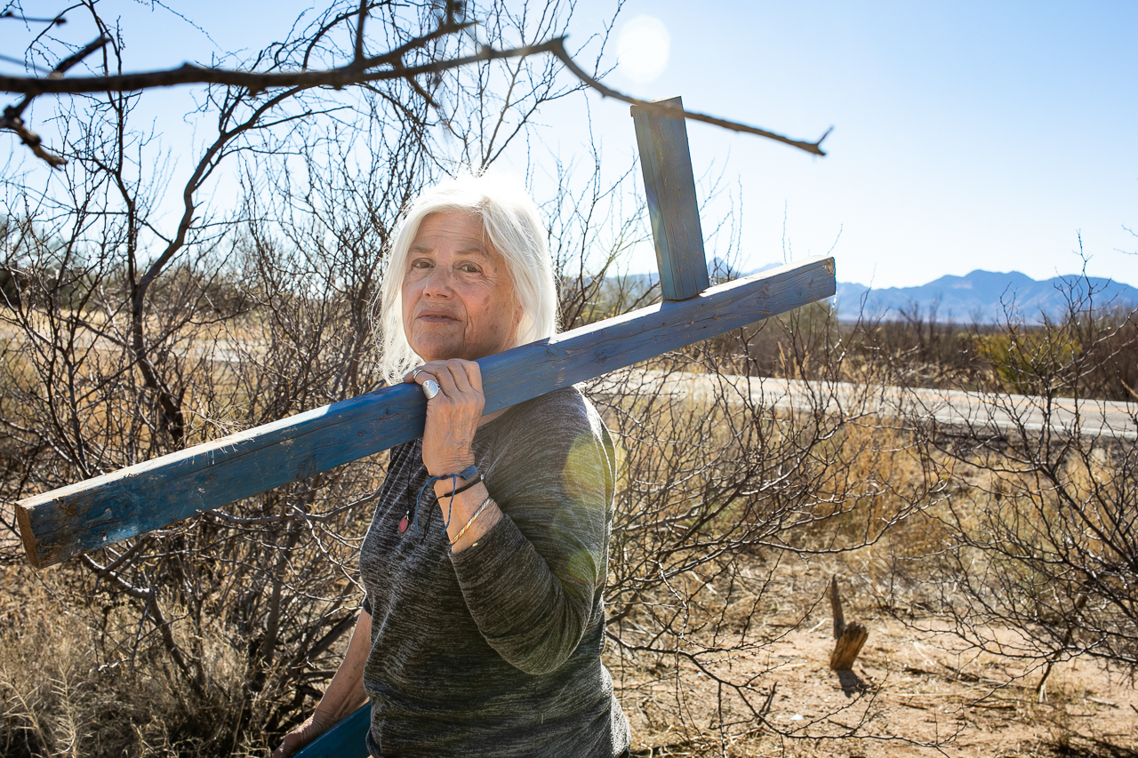 Tucson Samaritan Gail K. picks up a broken cross to bring it back to Tucson to be repaired.  The cross was placed at the location where an immigrant died traveling by foot in the desert. Tucson Samaritans given humanitarian aid such as leaving out water, blankets, and food along known travel routes.