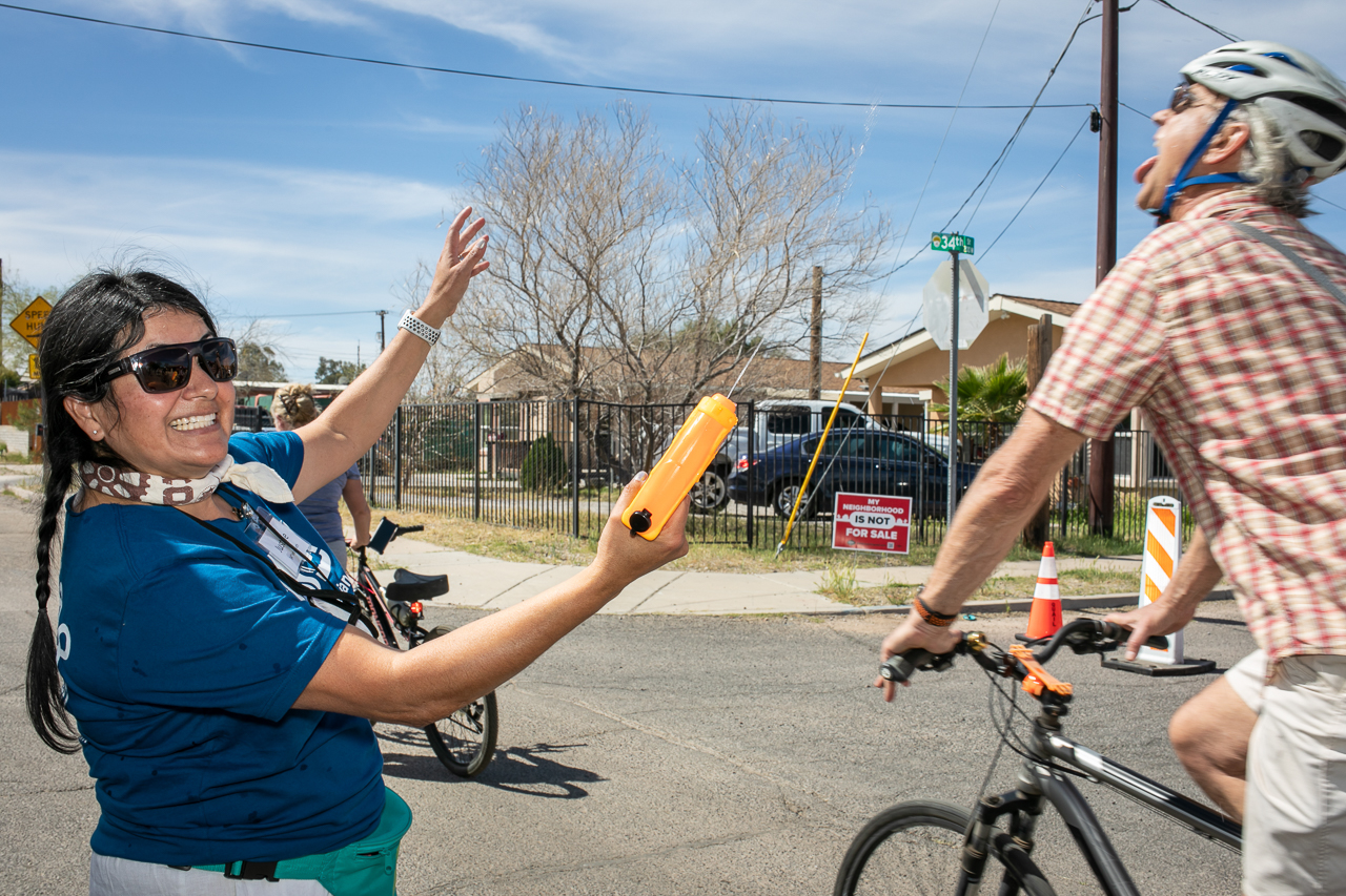 With nearly triple digit temperatures, a volunteer squirts water into the mouth of a passerby cyclist during Cylovia, a community event where people occupy the streets on a designated route including cyclists, skaters, walkers, joggers...people from all "walks of life".