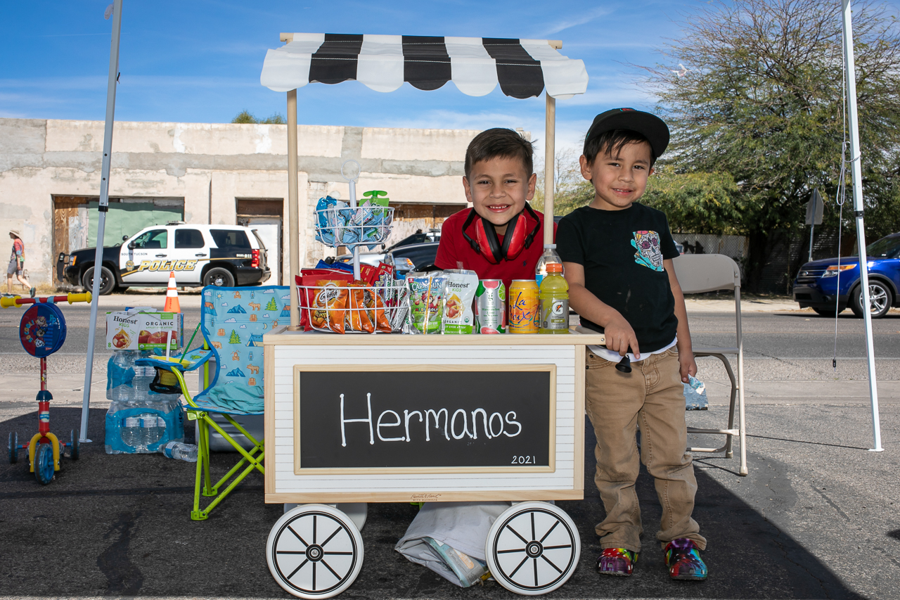 Two boys, with their watchful parents in sight, sell snacks during Cyclovia, a community event in which non-motorized traffic occupy city streets on a designated 4-5 mile route, including skaters, walkers, jogger, and cyclists.