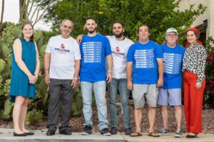 Representatives from Community Sponsorship Hub and Welcome Corps join the Kashmoola family in celebrating the reunion with their son and brother, Bahjat. Photo by Kathleen Dreier Photography outside the family home on 06/13/24.